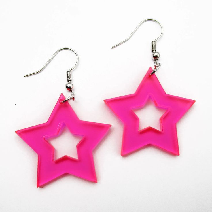 two starshaped earrings hang from metal hooks against a white background. the earrings are pink and feature a cutout star design.