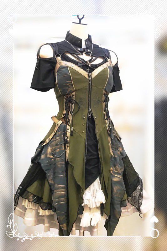a gothic steampunk style dress on a mannequin. the dress is predominantly olive green and black, featuring details like lace, a front zipper, straps, ruffles, a high collar, and a pendant. the skirt has an asymmetrical design with layers of different fabrics.