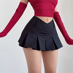 a woman is wearing a red top with a black pleated skirt. she is also wearing long red gloves. she is posing with one arm raised in the air.