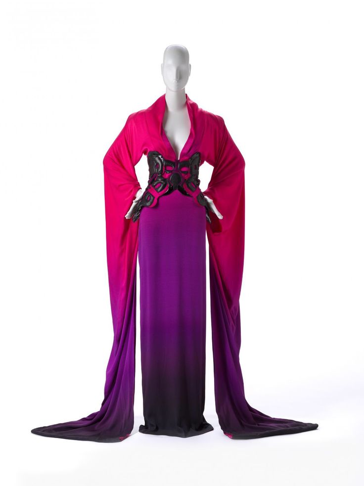 a mannequin wearing a pink and purple gradient formal gown with long flowing sleeves. the gown also features a black embellishment detail around the waist. the background is white.