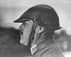 a black and white closeup portrait of a soldier from world war i, taken in profile. he is wearing a military helmet with a unique design. the photo captures his serious expression and the somber atmosphere of the time. the image is likely historical, dating back to the early 20th century.