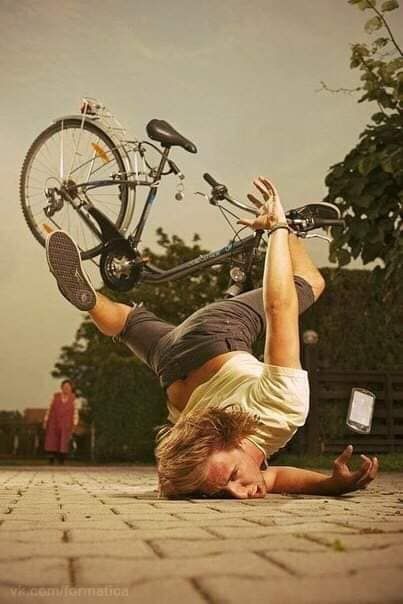 a man is falling off his bicycle onto a brick pavement. the bicycle is airborne above him, and a smartphone is falling from his hand. a woman is walking in the background.