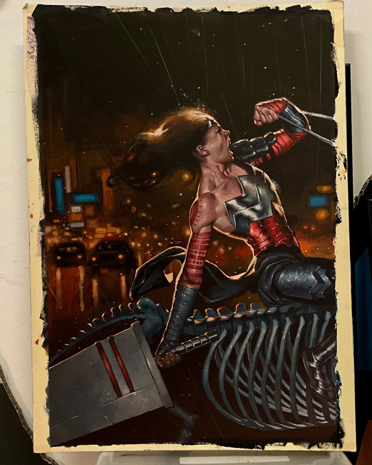 the image is a painting of wonder woman in an action pose with a hammer. she is on top of a skeleton with a city in the background. she appears to be yelling.