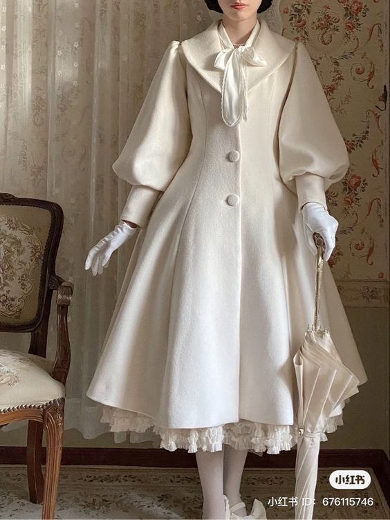 a woman is standing in a vintagestyle room, wearing a long, white coat with large, puffy sleeves and a lacetrimmed petticoat. she is holding a white umbrella in her right hand. the coat has a large collar and is buttoned up the front. the woman is also wearing white gloves and has her hair styled in a vintage updo. the room is decorated in a classic style with a wooden chair and a patterned wall.