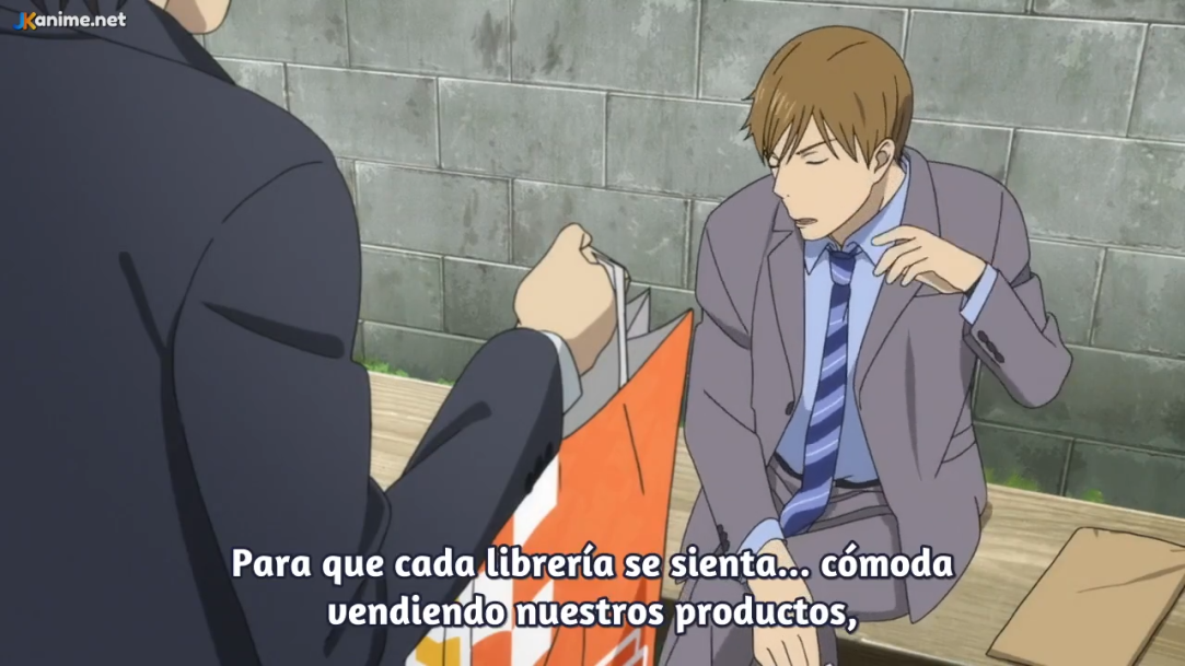 two men in suits are having a conversation on a bench outside. the man on the right is holding a shopping bag. the image appears to be a still from an anime. the subtitles at the bottom of the image read: "para que cada librería se sienta... cómoda vendiendo nuestros productos," which translates to: "so that every bookstore feels... comfortable selling our products."