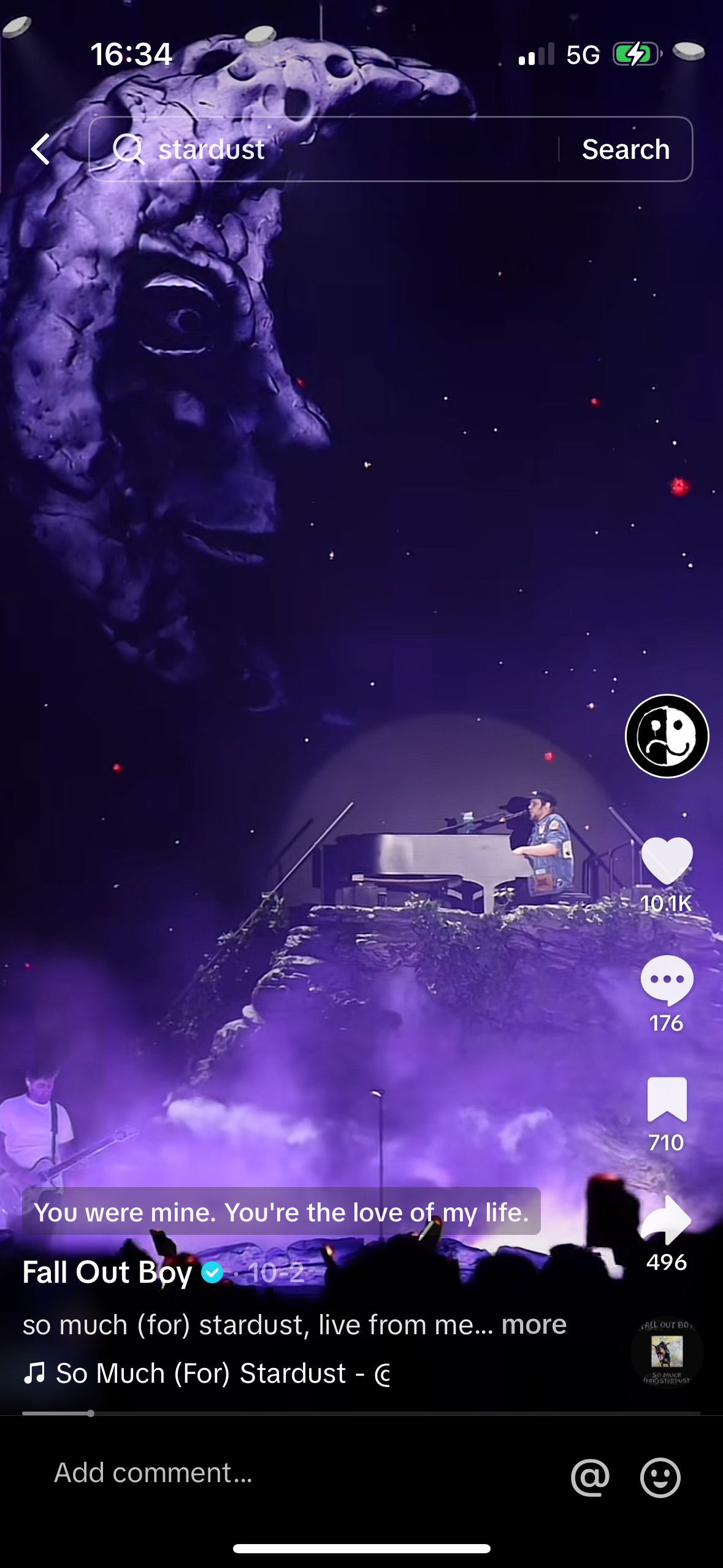 this is a screenshot of a music video from a concert performance. it features a singer playing a piano on a stage, with a crowd of people in the background. the video is being shared on social media with likes, comments, and views being displayed at the bottom of the screen. the name of the band and song are also visible, as well as the title of the video.