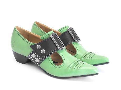 a pair of green mary jane shoes with a pointed toe and a low heel. the shoes have a black strap across the instep with a silver buckle and a studded strap. the background is plain white.