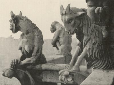 the image shows a series of stone sculptures, including two gargoyles and a monkey statue. the gargoyles appear to be hybrid creatures with animalistic and human features, including horns. they are positioned on a ledge, likely part of a building or architectural structure. the monkey statue sits in the middle. the sculptures are made of stone and have an aged appearance.
