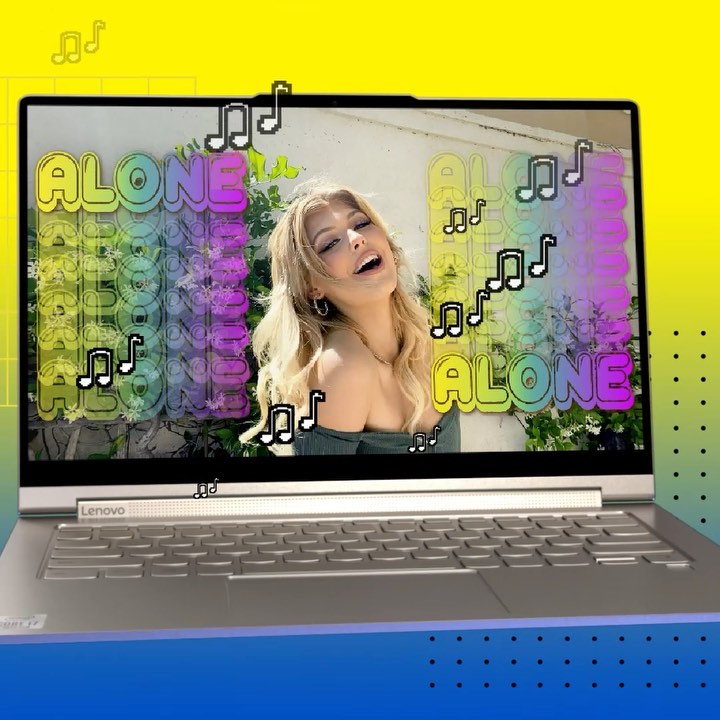 a laptop displaying a video of a woman singing with the word "alone" and music notes overlaid. the background is a gradient of yellow and blue. the laptop is a lenovo model.