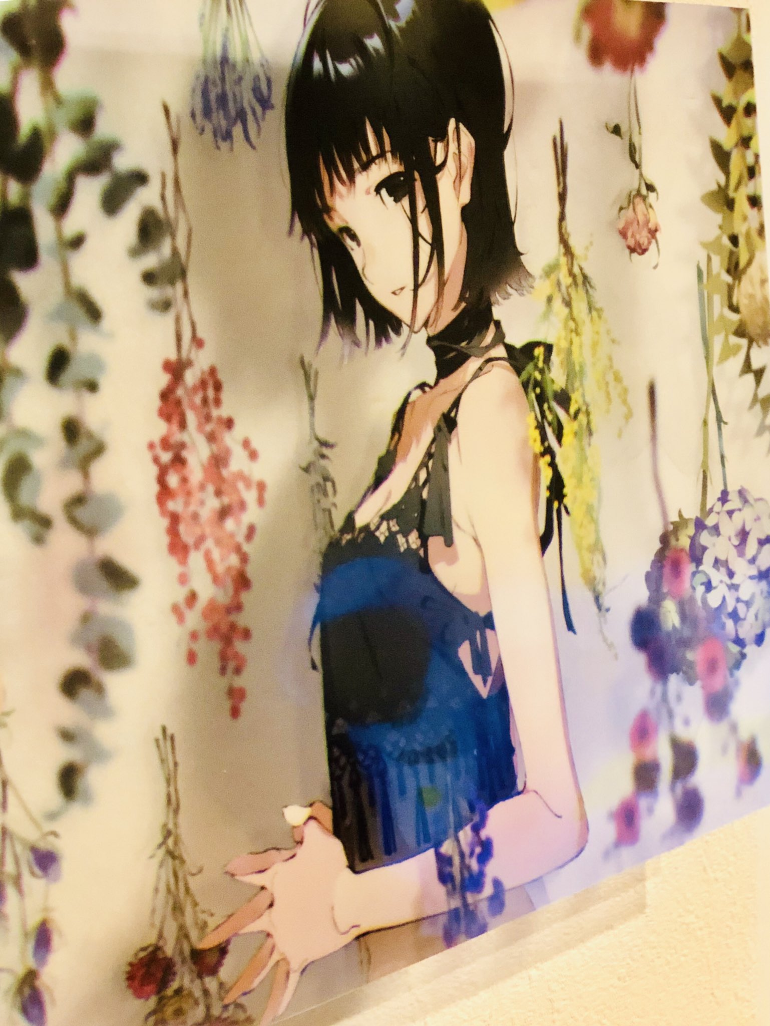 a wall scroll of an anime girl with short black hair, wearing a black dress, is hanging on a wall. the background is transparent and features numerous colorful flowers. the lighting appears to be bright and artificial. the perspective of the image is at eye level.