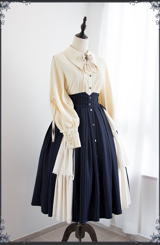 a cream and navy blue lolita fashion dress is shown on a mannequin in a studio setting. the dress features a highwaisted, pinstriped skirt with a buttonup front and a flowing, asymmetrical creamcolored panel. the bodice is a separate cream blouse with a large collar, laceup detailing on the sleeves, and a pleated front.
