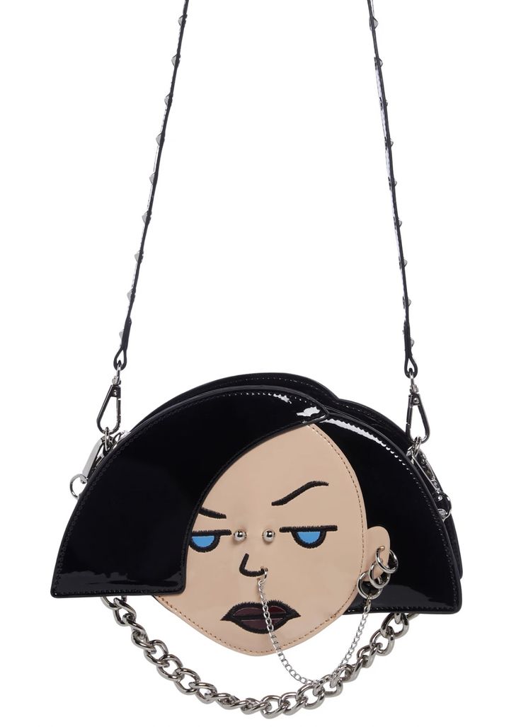 a purse that looks like a cartoon face with piercings and a chain below it. the purse has a strap with studs.