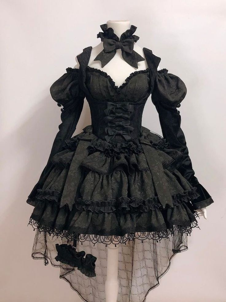 a black, gothic lolita style dress is displayed on a white mannequin. the dress features multiple layers of ruffles, lace, and frills. it has a corsetstyle bodice with bows, offtheshoulder long sleeves with puff detail, and a highlow hemline. the dress also includes a collar with a large bow and a damask pattern throughout.