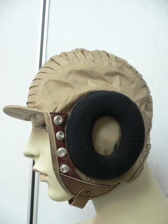 a closeup of a vintage beige aviator hat with brown leather ear flaps and straps.  the hat has a large donutshaped earmuff on the right side. the hat is being worn by a mannequin.