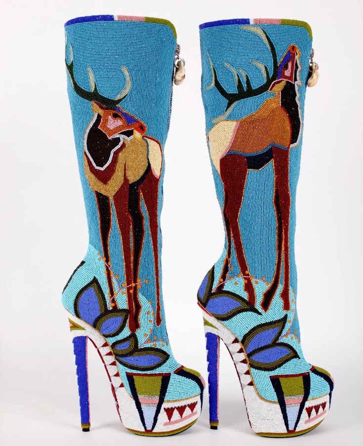 a pair of exquisitely crafted highheeled boots are showcased against a stark white background. the boots, extending to the knee, are adorned with intricate beadwork depicting elk figures.  the vibrant turquoise base color is complemented by other colors, such as brown, red, and white, in the beadwork design.  the heels are exceptionally high and feature a platform sole.  the boots exhibit highquality craftsmanship and artistic expression, blending fashion with traditional native american artistry.  the detailed beadwork is a focal point, demonstrating a high level of skill and attention to detail. the style is both modern and traditional, presenting a unique fusion of styles.