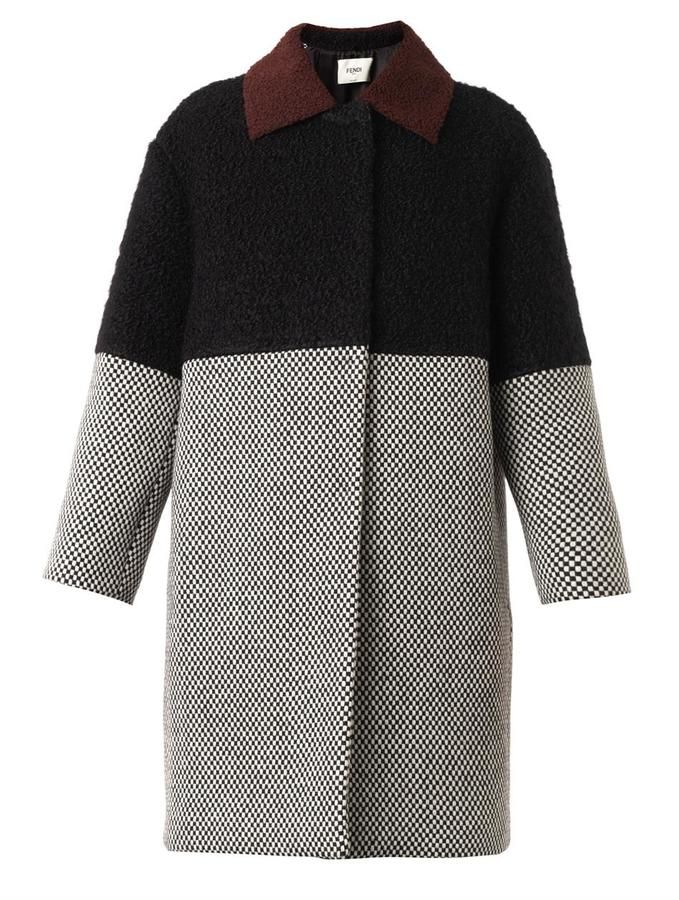 the image shows a fendi kneelength color block coat with a checkerboard pattern on the lower half and sleeves and a solid black texture on the upper half. it has a brown collar.
