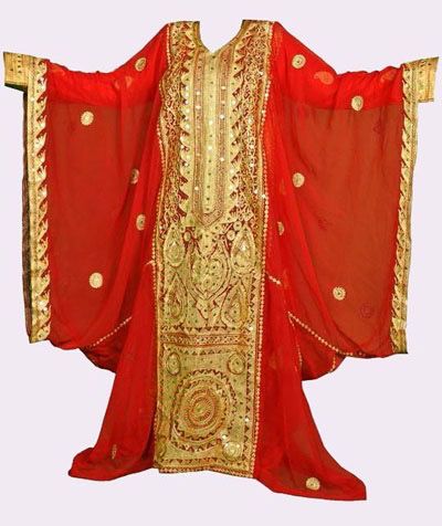 the image shows a full view of a red caftan dress with elaborate gold embroidery. the dress is made of a flowing chiffonlike fabric and features wide sleeves. the gold embroidery is intricately designed and covers the central part of the dress and the sleeve edges. the design suggests traditional middle eastern or arabic clothing suitable for formal events or cultural celebrations.
