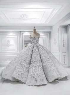a stunning white wedding dress with intricate lace detailing and a full, voluminous skirt. the dress is on a mannequin and is in a white room with beautiful ornate ceiling moldings. the dress has a sweetheart neckline and is off the shoulder. it is a classic and elegant design that would be perfect for a bride who wants to look and feel like a princess on her wedding day.