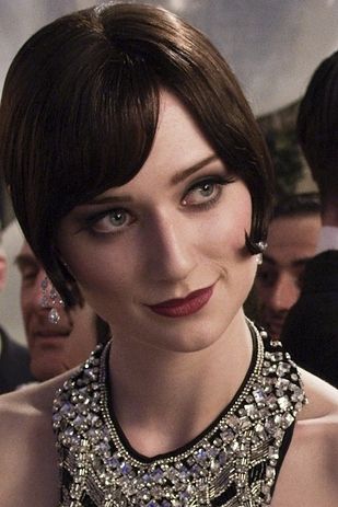 a glamorous woman in a vintage 1920s flapper style dress, smiling and looking at the camera. she is wearing a dazzling, sparkling necklace and her hair is styled in a chic bob. the image is close up, with the focus on the woman's face. she looks elegant and sophisticated, and the overall mood is one of joy and celebration.