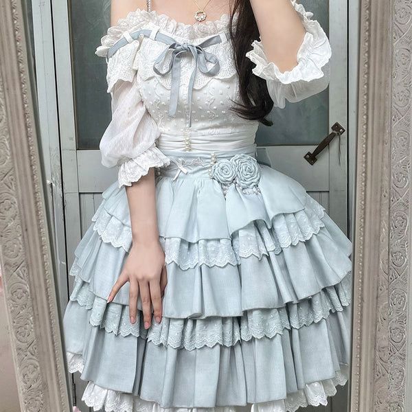 a young woman is taking a mirror selfie showcasing a lolita fashion outfit. she is wearing a baby blue tiered skirt with lace trim, a white offshoulder blouse with lace and ribbon details. the overall look is very feminine and delicate.