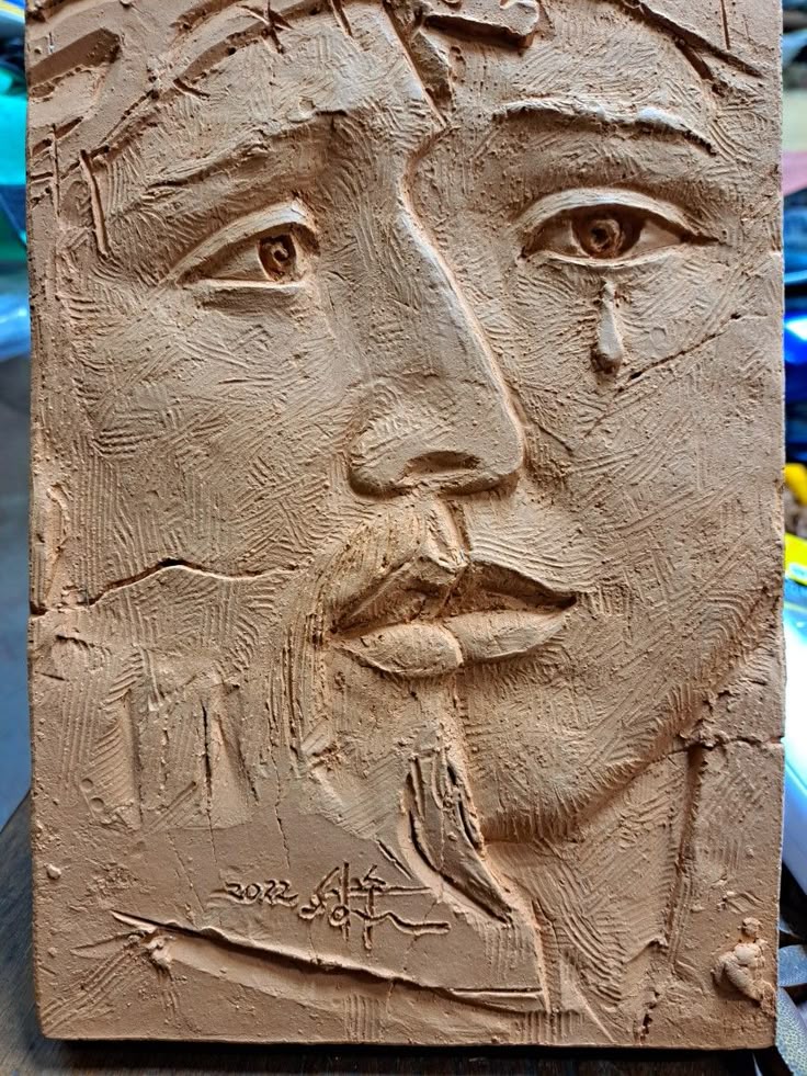 the image shows a clay sculpture of a man, likely jesus christ, with a crown of thorns. the artwork is a closeup portrait, featuring a sad expression with a tear falling from one eye. the sculpture is signed by the artist in korean with the date 2022. the overall impression is one of religious suffering and emotion.