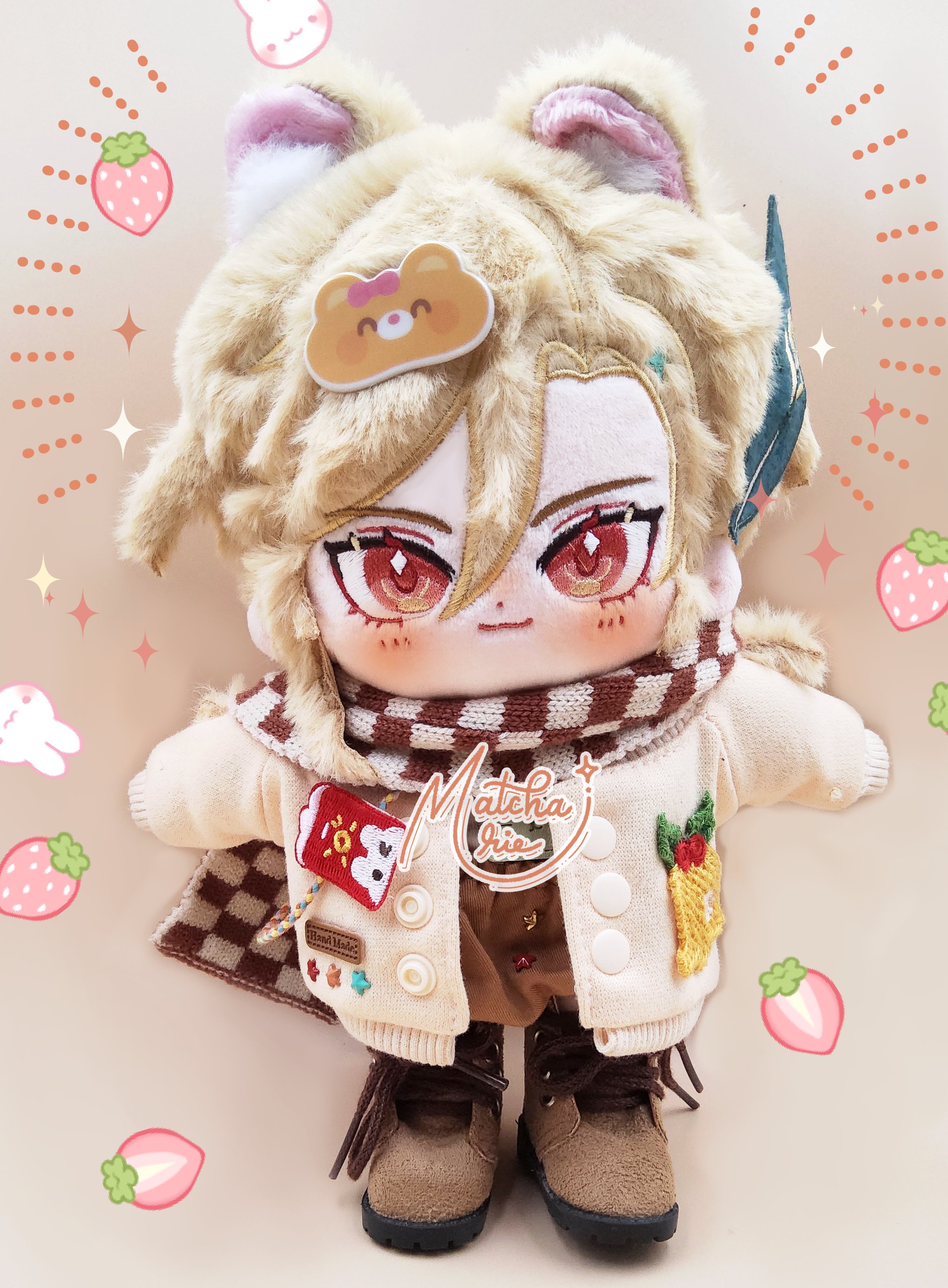 a cute plush toy of a boy wearing a brown hat, white sweater and brown scarf with boots, with white fur and red eyes. he is standing on a brown surface with a white background and the words "matcha iris" in white letters on a brown background.  there are also some white and red hearts and strawberries surrounding the doll.