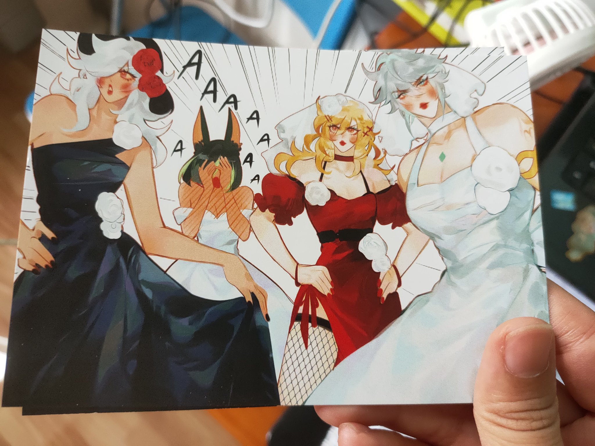 the image shows a closeup photograph of an animestyle postcard or print. the artwork depicts four female characters in various dresses. one is in a black dress, another in a red dress, a third in a white dress, and a fourth in a pale bluewhite wedding dress.  the character in the red dress is centerstage. the characters have exaggerated features and expressions; three appear shocked or surprised, as indicated by their expressions and the "aaa" speech bubbles.  the art style is reminiscent of manga or anime, and the background suggests a comicbookstyle panel with speed lines. the postcard is held in someone's hand.