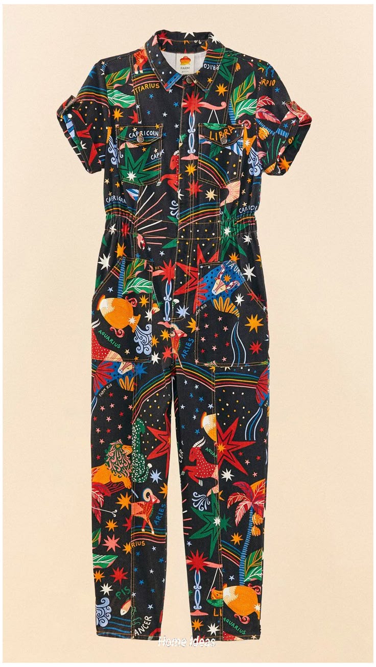 a black, shortsleeved jumpsuit with an astrological zodiac pattern is displayed against a light beige background. the jumpsuit has a buttondown front, two breast pockets, and cuffed sleeves. the pattern includes various zodiac signs, stars, and colorful designs.