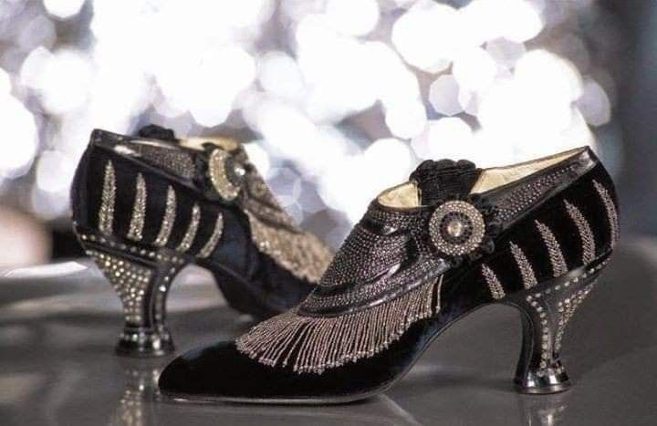a closeup shot of a pair of vintage black heeled shoes. the shoes have a lot of sparkling rhinestones embellishments on them, and they look very classy and elegant.