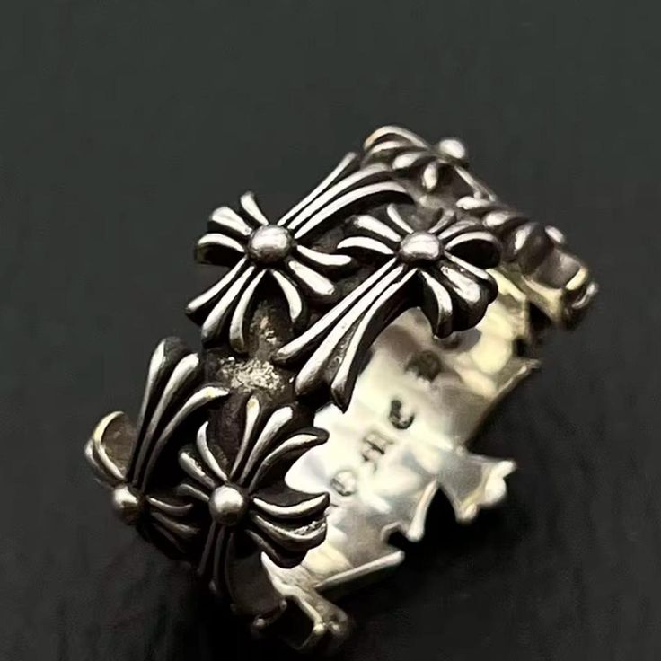 a closeup shot shows a silver ring adorned with multiple ornate cross designs. the ring appears to be of a band style, with the crosses arranged around its circumference.