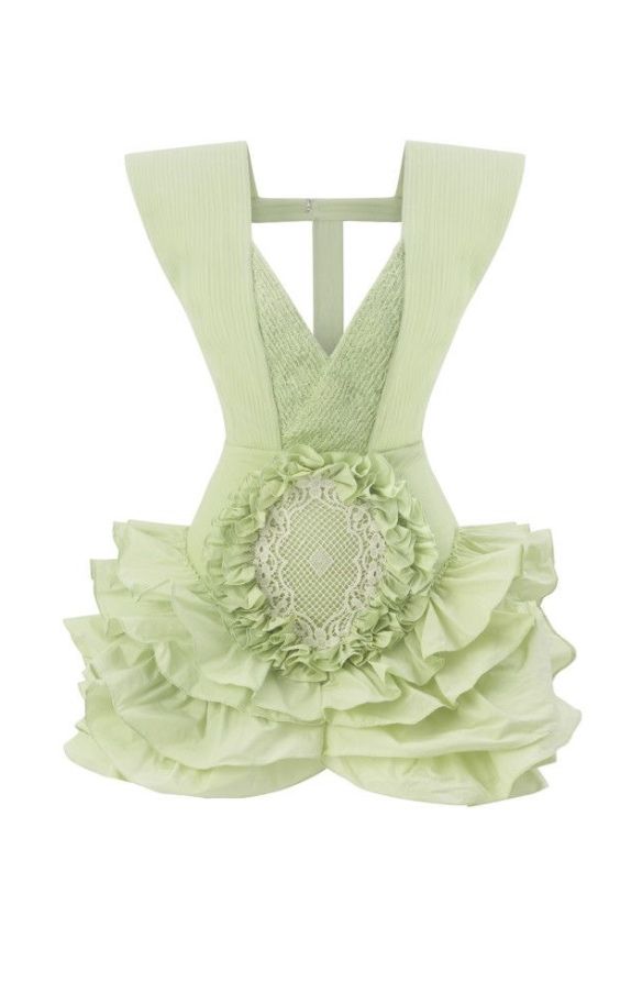 a pale green apron with ruffled layers and a lace decorative element in the center of the apron's body is isolated on a white background.