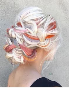 a woman with long blonde hair that has been styled with a braid and then twisted into a bun. the hair is also colored with streaks of pink and orange. the woman is looking away from the camera.