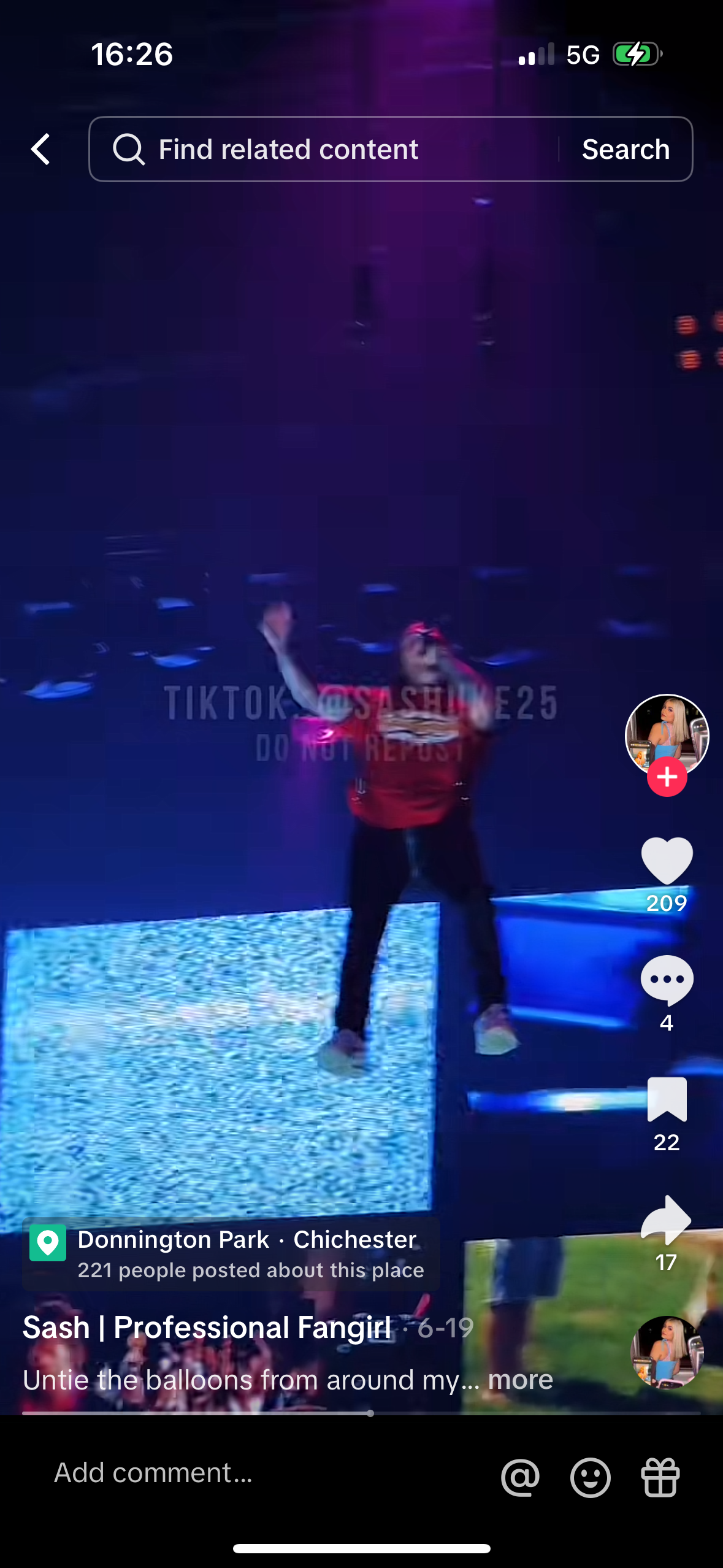 a woman is singing on stage in front of a crowd. she is wearing a red shirt and black pants, her hair is pink. the video was filmed on a phone, and in the background, there are fans who are filming her and waving. the tiktok interface appears at the bottom with a lot of information about the user and the video.
