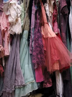 a rack of clothing with a variety of dresses and fabrics in a variety of colors. the dresses are all flowing and delicate, and they have a vintage feel to them. the colors are soft and feminine, and the fabrics are luxurious. the clothing is displayed on a rack in a shop or boutique, and it looks like it would be perfect for a special occasion.