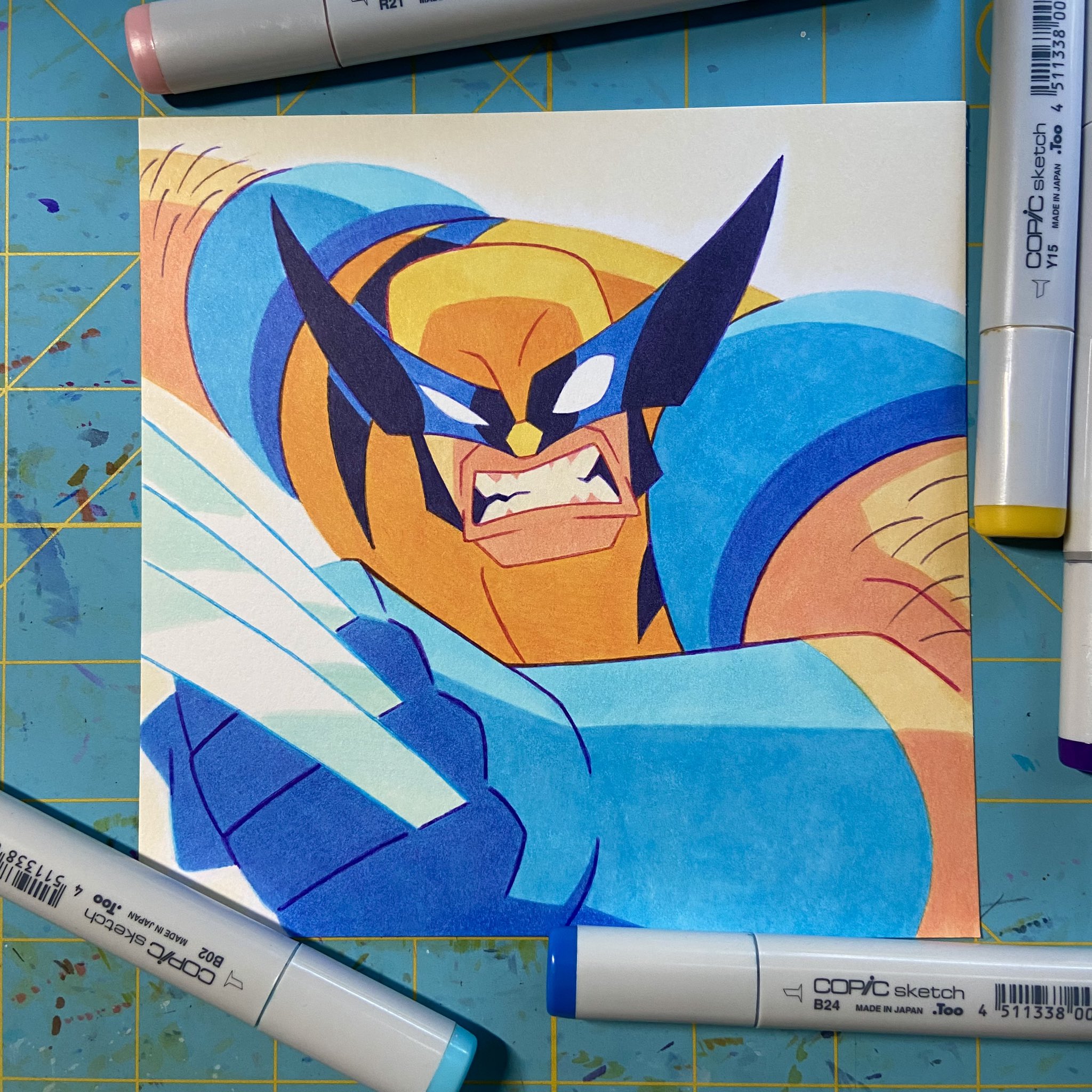 a drawing of wolverine, a marvel superhero, drawn with copic markers. it is a cartoon illustration of the character. wolverine is in a fighting pose, ready to attack, with his claws extended. the drawing is done on a white paper with a blue background.