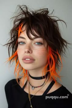 a young woman with messy dark brown hair with orange highlights and a black choker around her neck looks directly into the camera.