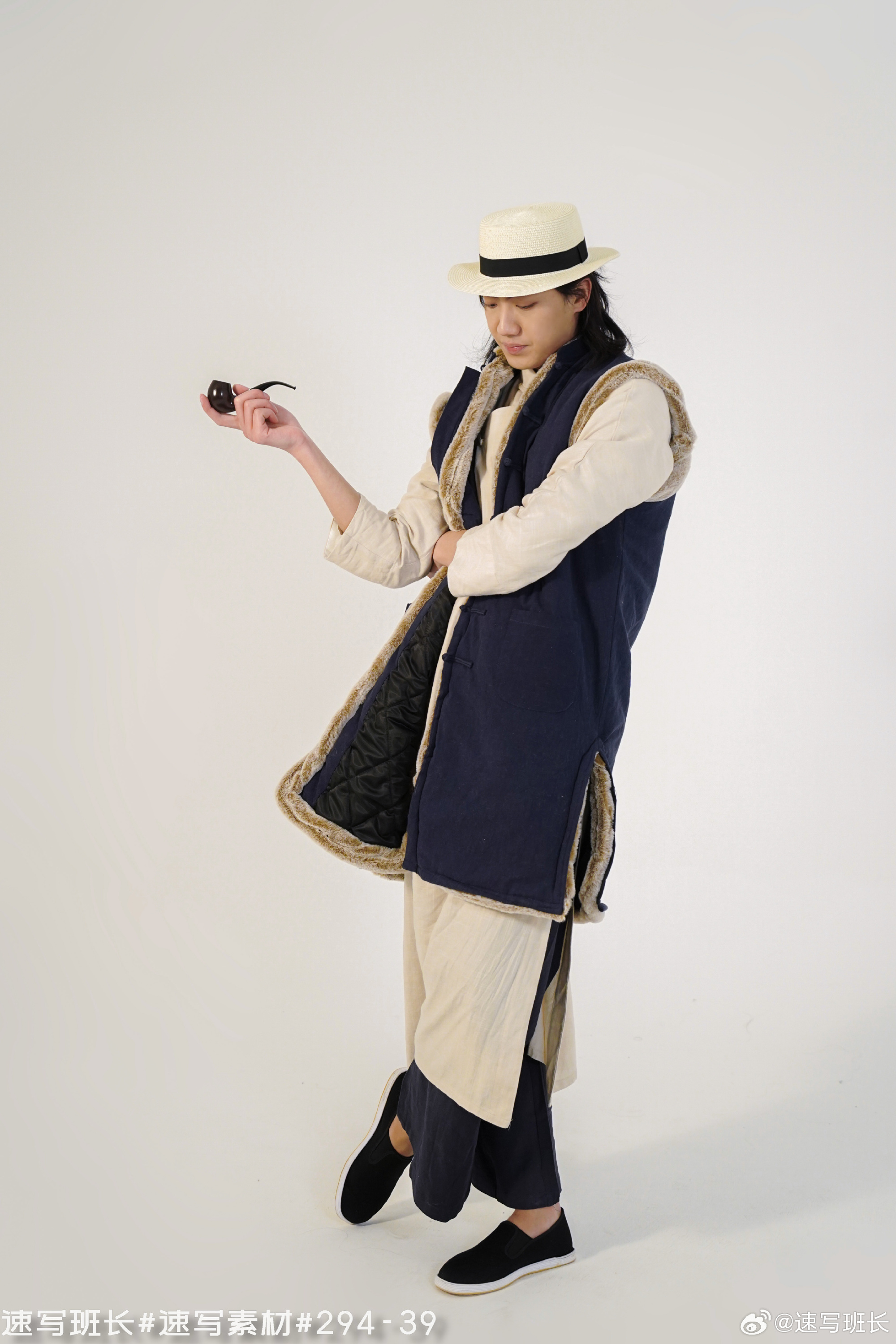 a man wearing a straw hat and a long, navy blue vest with fur trim is holding a pipe.  he is dressed in a style that appears to be inspired by traditional chinese clothing. the background is white.