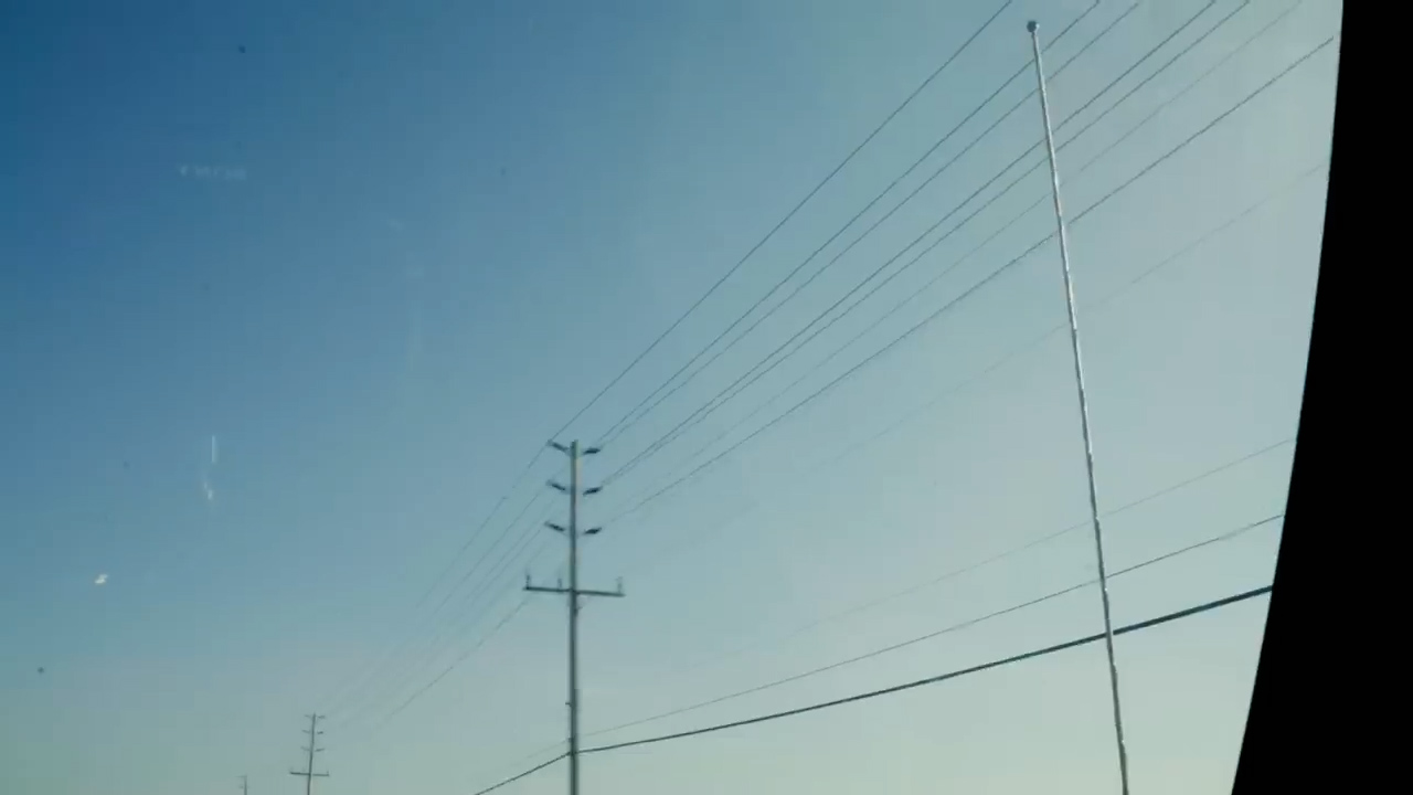 this is an outdoor, low angle view of a clear blue sky with some wispy clouds. there are power lines and poles in the image.