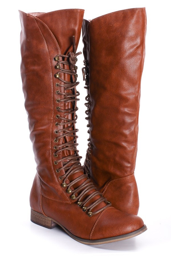 a pair of brown leather kneehigh boots with laceup detailing are shown in the image. the boots have a flat heel and a side zipper for easy on and off. the boots are made of a faux leather material and have a slightly slouchy fit.  one boot is slightly in front of the other. the background is white.