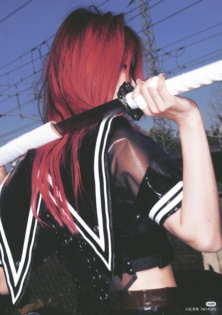 a woman with red hair is holding a katana over her shoulder. she is wearing a black and white sailor outfit. the background is a blue sky with power lines.