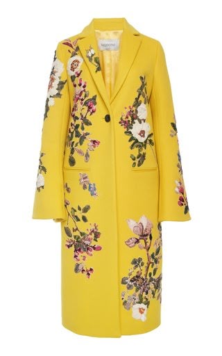 a full shot of a yellow valentino coat with floral embroidery on a white background. the coat has a singlebutton closure, a notched lapel, and long sleeves. the embroidery features pink, white, and purple flowers with green leaves.
