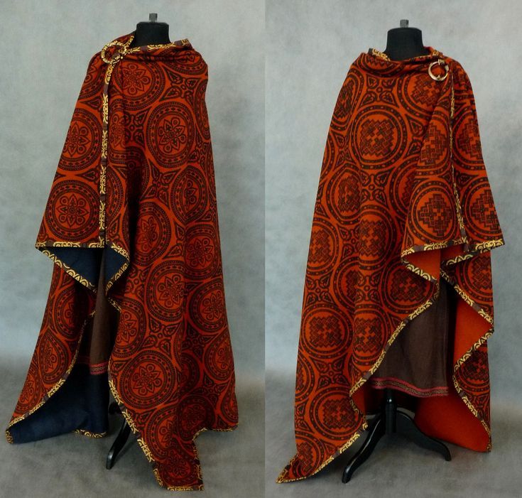 the image shows two mannequins wearing intricately patterned cloaks. the cloaks are primarily orange with brown circular patterns and gold trim along the edges. the mannequins are standing against a plain background, allowing the focus to remain on the clothing. the cloaks are secured at the collar with a circular clasp, giving them a historical or fantasyinspired appearance. the overall aesthetic suggests a medieval, gothic, or cosplay theme.