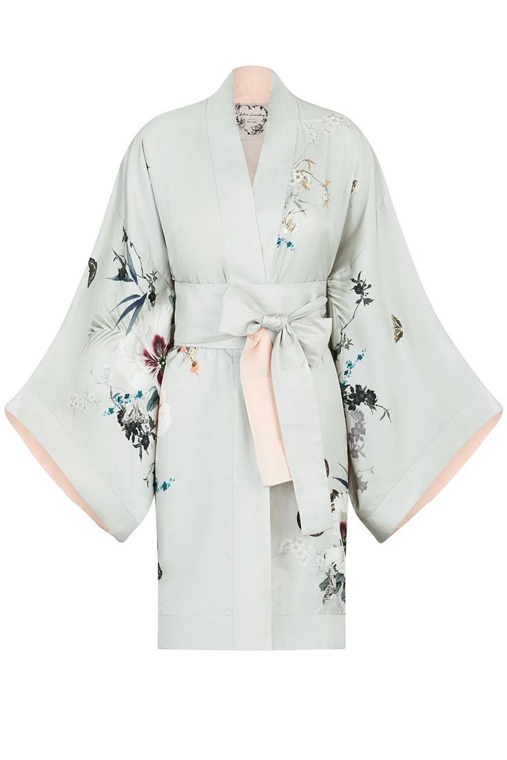 a light green silk kimono with floral patterns in a variety of colors, including pink, white, and green. the kimono is trimmed with a delicate pink trim. it is tied with a wide pink sash. the kimono is a stylish and elegant piece of clothing. it would be perfect for a relaxing evening at home or a special occasion.