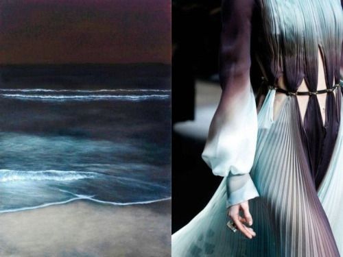a woman wearing a flowing, pleated dress with a gradient of blue, green, and purple colors. the dress has a silver belt and is styled in a high fashion manner. the background features a sunset scene with an ombre effect of dark blue and light blue colors, resembling the ocean with waves. the image captures a blend of fashion and nature, showcasing the elegance and beauty of both.