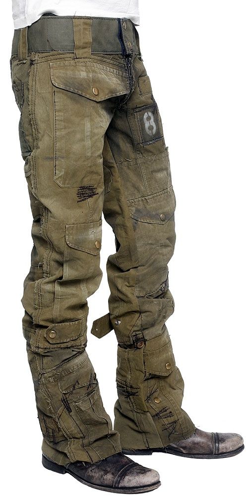 a photo of a man wearing a pair of militarystyle cargo pants. the pants are green and have many pockets, and are ripped and distressed in some areas. the man is wearing a white tshirt under the pants.