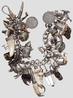 a silver charm bracelet with many ornate charms, including a bird, a skull and bones, a claw, and other animalthemed designs. it's a beautiful and intricate piece of jewelry, likely a vintage or antique item.