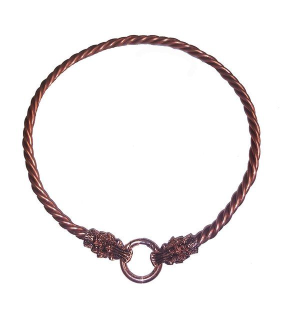 the image shows a coppercolored torquestyle necklace. the necklace is made of a twisted metal cord, and the ends feature detailed dragon head designs. the two dragon heads are connected by a circular clasp. the necklace is photographed against a white background.