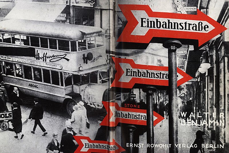this is a photomontage image, likely a book cover, featuring a busy city street scene in berlin.  the most prominent elements are several red and white "einbahnstraße" (oneway street) signs in a prominent position, creating a visual emphasis.  a doubledecker bus with advertising for "hoffmanns" and "aboag" is partially visible in the left half of the image.  many pedestrians are shown walking in the street below. the text "walter benjamin" and "ernst rowohlt verlag berlin" are visible, indicating authorship and publication details.  the overall style is reminiscent of photomontage art popular in the 1930s. the image contrasts sharp, bold elements (the signs) with a more chaotic, documentary style depiction of the street scene.