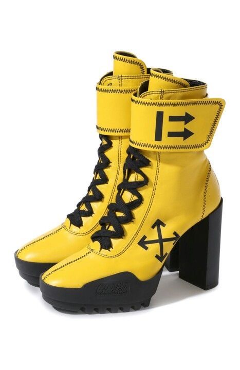 a pair of yellow offwhite high heel boots with black laces, black stitching and a black heel. the boots are made of leather. the image shows a pair of boots, one of them is on top of the other.