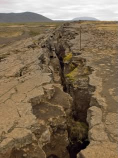 a view of a fissure in the ground, probably caused by tectonic plate movement.  the fissure is wide and deep, and the ground on either side is cracked and broken.  the ground around the fissure is dry and barren, with no vegetation.  the image is taken from a high angle, looking down on the fissure.
